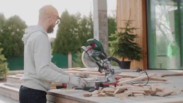 Mann Sägt Mit Tischsäge Holz Auf Baustelle Eines Modernen Holzhauses — Stockvideo