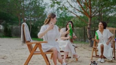 Gençler sahildeki kamp ateşinde oturup selfie çekiyorlar. Bir grup arkadaş ormanda kamp ateşinde oturup fotoğraf çektirmek için şişe tezahüratı yapıyor. Yüksek kalite 4k görüntü