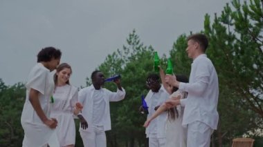 İnsanlar gün batımında ormanda parti veriyor. Bir grup arkadaş akşamları kamp alanında dans edip eğleniyorlar. Beyaz elbiseli insanlar içiyor ve eğleniyorlar. Yüksek kalite 4k görüntü