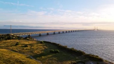 Aerial view of Oresund bridge at the sunset in summer. Cinematic shot of long tunnel and bridge between Sweden and Denmark. Oresund bridge from the side. High quality 4k footage