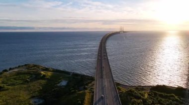 Drone flying over Oresund bridge at the sunset in summer. Cinematic shot of long tunnel and bridge between Sweden and Denmark. Oresund bridge in the middle of the shot. High quality 4k footage