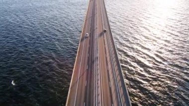 Drone flying over an Oresund bridge at the sunset in summer. Cinematic shot of long tunnel bridge between Sweden and Denmark. Cars driving on a huge bridge shot from the top. High quality 4k footage