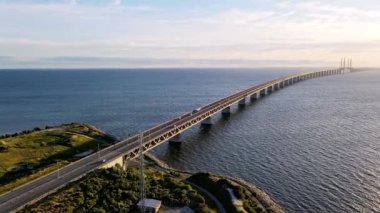 Aerial view of Oresund bridge at the sunset in summer. Cinematic shot of long tunnel and bridge between Sweden and Denmark. Oresund bridge from the side. High quality 4k footage