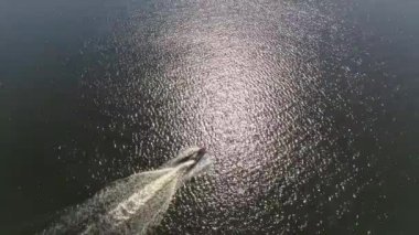 Şehrin göletinde kırmızı beyaz bir jet ski süren bir adamın hava görüntüsü. Yaz güneşli bir gün