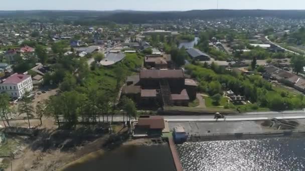 池の隣の木々の間の都市の郊外に鉄の屋根を持つ古い赤レンガ工場の空中ビュー 夏の晴れた日 — ストック動画