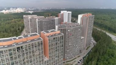 Bulutlu bir günde otobanın yanındaki binaların insansız hava aracı görüntüleri. Ormanla çevrili park yeri ve arabalarla birlikte kamu binasının üzerinde havadan çekilmiş bir fotoğraf. Kasvetli bulutlu gökyüzü. Otoyolda sürüş yapan bir sürü araba var.