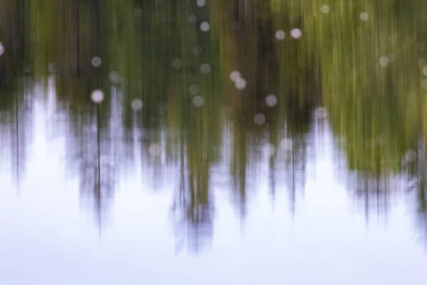Абстрактная рябь воды отражающая лес и небо — стоковое фото
