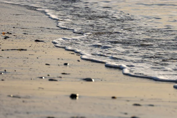 Темные силуэтированные породы с волнами качения и песком — стоковое фото