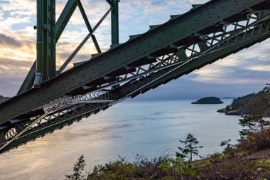 Okyanus üzerinde bulutlu bir gün batımı bir köprünün iskeletinde