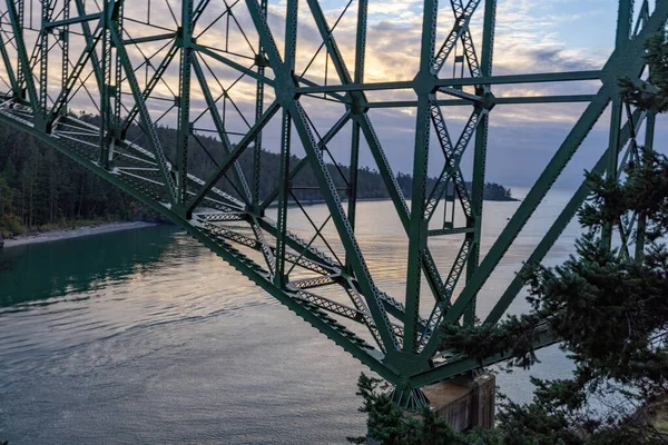 Okyanus üzerinde bulutlu bir gün batımı bir köprünün iskeletinde