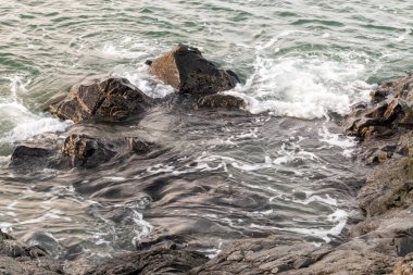 Dalgalar bir uçuruma çarpıyor ve kayaların etrafında toplanıyor.