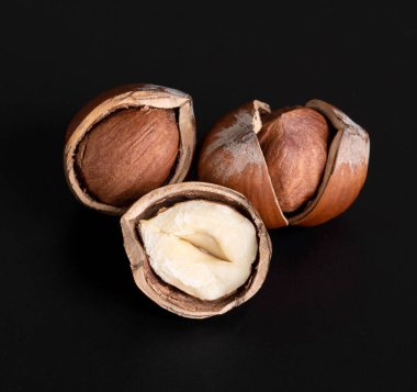 Parlak, siyah bir arka planda üç güzel çatlak fındık. Üst Manzara. Yakın plan.