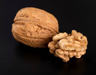 Güzel desenli bir ceviz kabuğu ve siyah arka planda bir ceviz çekirdeği. Yakın plan.