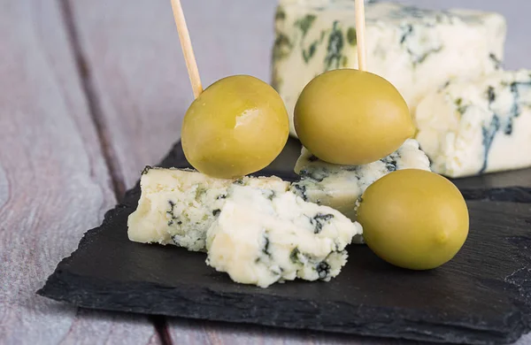 黒スレートボード上の青カビや大規模な緑のオリーブチーズ — ストック写真