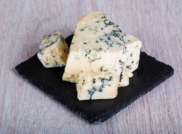 スレートボード上の青カビ ゴルゴンゾーラ ロックフォール スティルトン ダナブリン とおいしい香りのチーズのいくつかの作品 — ストック写真