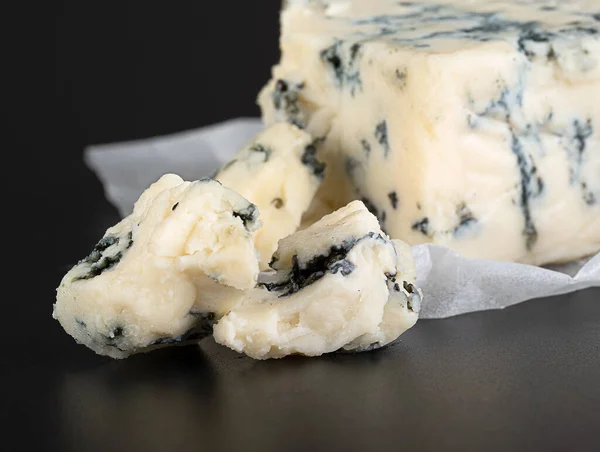 白いクラフト紙の中に反射して黒の背景に型を持つチーズ — ストック写真