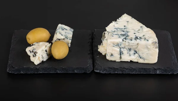 青い型と青い型と大きな緑のオリーブとチーズのいくつかの小さな部分を持つチーズの大きな部分 — ストック写真