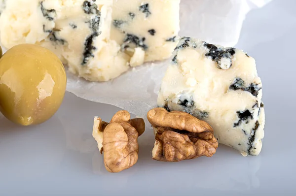 反射して黒の背景に白いクラフト紙にオリーブとクルミと型を持つチーズ — ストック写真