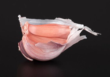 Pembe kabuklu sarımsak, parlak siyah bir arkaplanda, yansımalı.