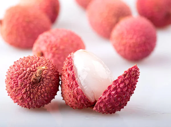 Kabuklu ve soyulmuş lychee beyaz arka planda izole edilmiş.