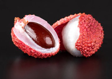 Lychee ve yarım lychee siyah arka planda izole edilmiş.