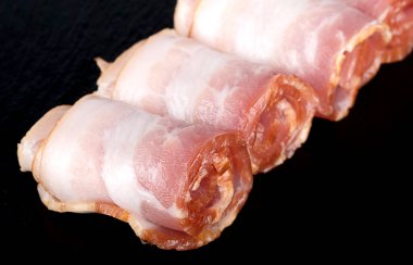 Güzel katlanmış pastırma parçası siyah bir arka planda izole edilmiş. Yakın plan.