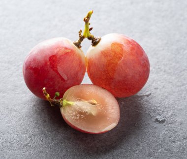 Bir dalda tam üzüm ve gri desenli arka planda ikiye bölünmüş üzümler. Makro fotoğrafçılık. yakın plan