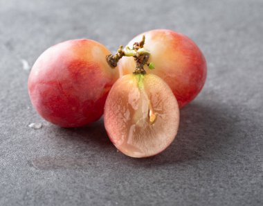 Bir dalda tam üzüm ve gri desenli arka planda ikiye bölünmüş üzümler. Makro fotoğrafçılık. yakın plan