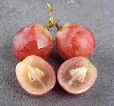 Bir dalda tam üzüm ve gri desenli arka planda ikiye bölünmüş üzümler. Makro fotoğrafçılık. yakın plan
