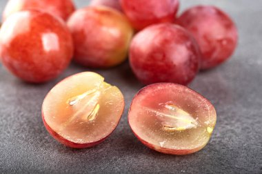 İki yarım dilim sulu üzüm gri desenli arka planda bir demet üzüm. Bulanık arkaplan