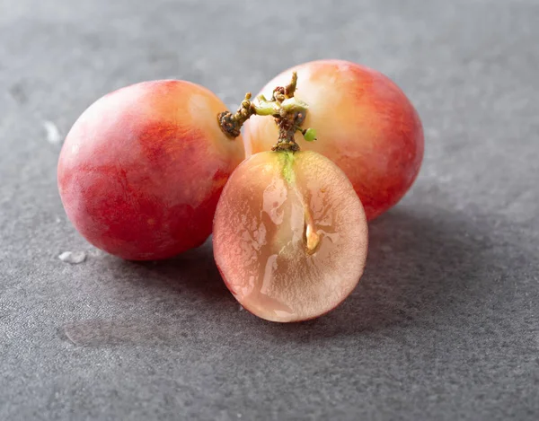 Bir dalda tam üzüm ve gri desenli arka planda ikiye bölünmüş üzümler. Makro fotoğrafçılık. yakın plan