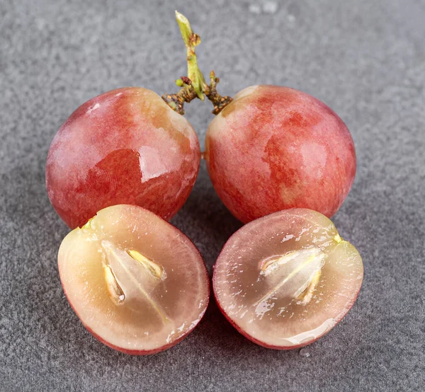 Bir dalda tam üzüm ve gri desenli arka planda ikiye bölünmüş üzümler. Makro fotoğrafçılık. yakın plan