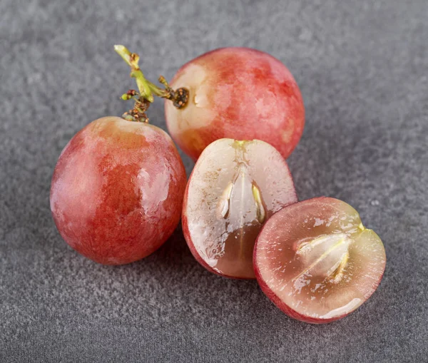 Bir dalda tam üzüm ve gri desenli arka planda ikiye bölünmüş üzümler. Makro fotoğrafçılık. yakın plan