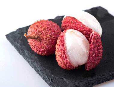 Kabuklu ve soyulmuş lychee beyaz arka planda izole edilmiş.