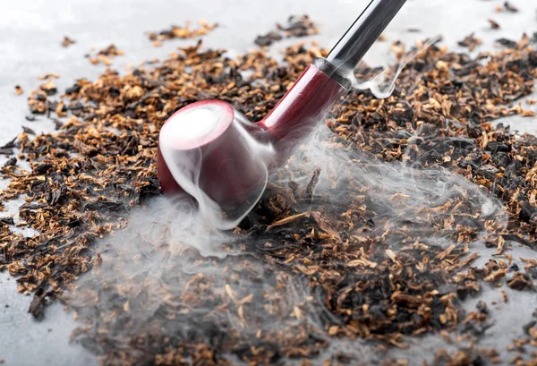 タバコの背景に煙の美しいストリームを持つ木製の喫煙パイプ ストック画像