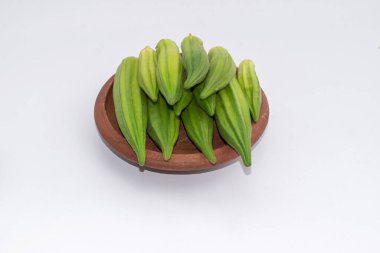 Fresh okra (Lady Finger) in earthen bowl on white background.