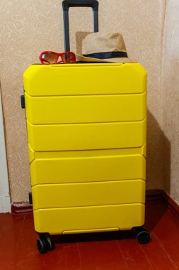 Sarı çantalı, güneş gözlüklü ve şapkalı bir oda. Seyahat kavramı