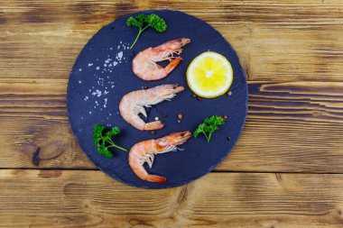 Tahta tahtada limonlu, maydanozlu, tuzlu ve biberli büyük çiğ karidesler. Üst görünüm