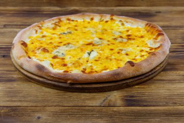 Tahta arka planda dört peynirli pizza.