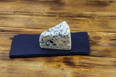 Ahşap masada siyah tahta servis edilen küflü mavi peynir.