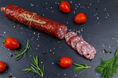 Siyah tahta üzerinde vişneli domates ve baharatlı salam sosisi. Üst görünüm