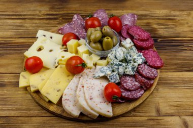 Zeytinli, kiraz domatesli, ahşap bir masada İtalyan salamı ve peyniri karışımı.