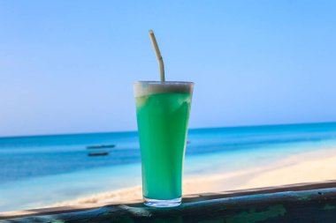 Okyanus kıyısında bir bardak Mavi Hawaii kokteyli.