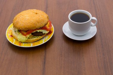 Lezzetli hamburger ve bir fincan kahve ahşap masada
