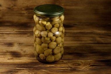 Ahşap masada cam kavanozda marine edilmiş lezzetli mantarlar.