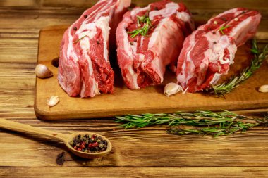 Baharatlı çiğ domuz kaburgası, sarımsak ve ahşap masada biberiye.