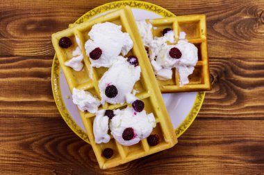 Dondurmalı Belçika waffle 'ı ve ahşap masada böğürtlen.