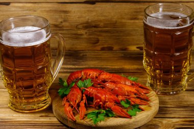 Haşlanmış kerevit ve tahta bir masada iki kupa bira.
