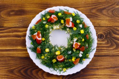 Tahta bir masada salata Noel çelengi. Üst görünüm