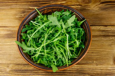 Tahta bir masada seramik kasede taze yeşil roka. Sağlıklı gıda veya vejetaryen konsepti
